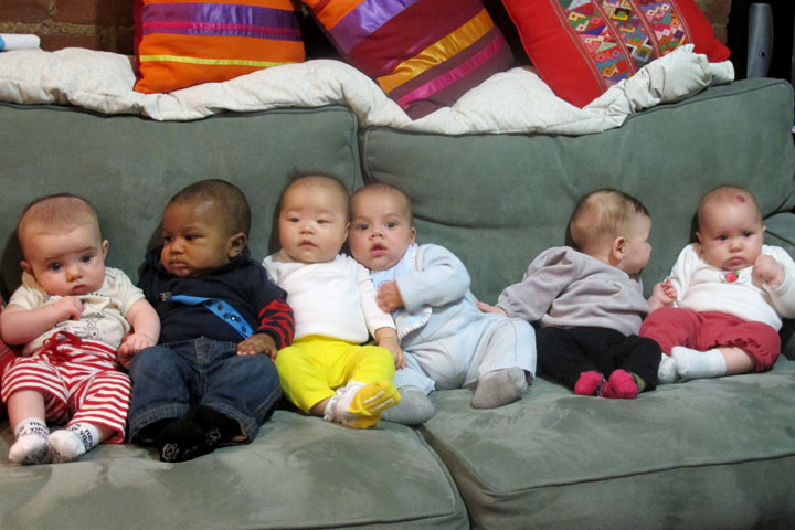 Babies lined up on a couch