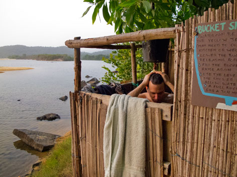 Tribewanted guest using bucket shower, Sierra Leone