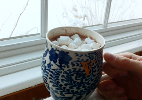 Hot chocolate with marshmallows in winter, before a snowy background