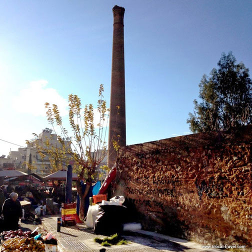 Perissos farmers market in Athens, Greece, with abandoned chimney in background