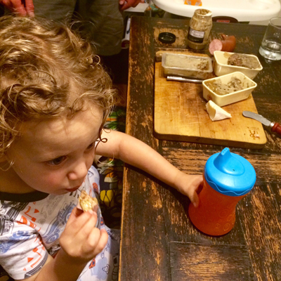 Toddler boy eating charcuterie.